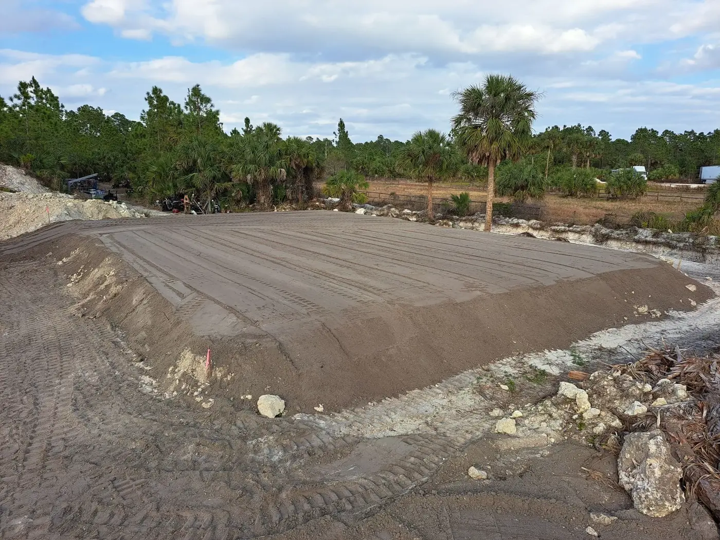Raised dirt house pad with packed, sloped sides on a cleared lot